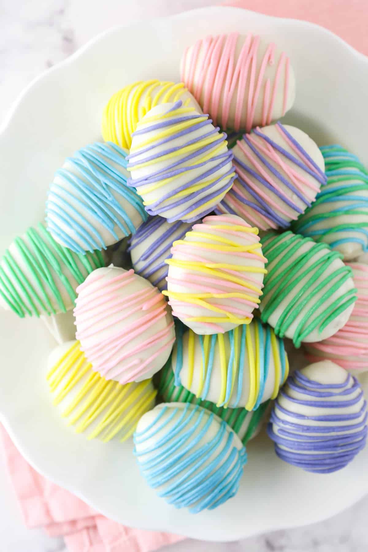 Easter egg Oreo cookie balls stacked on a white plate.