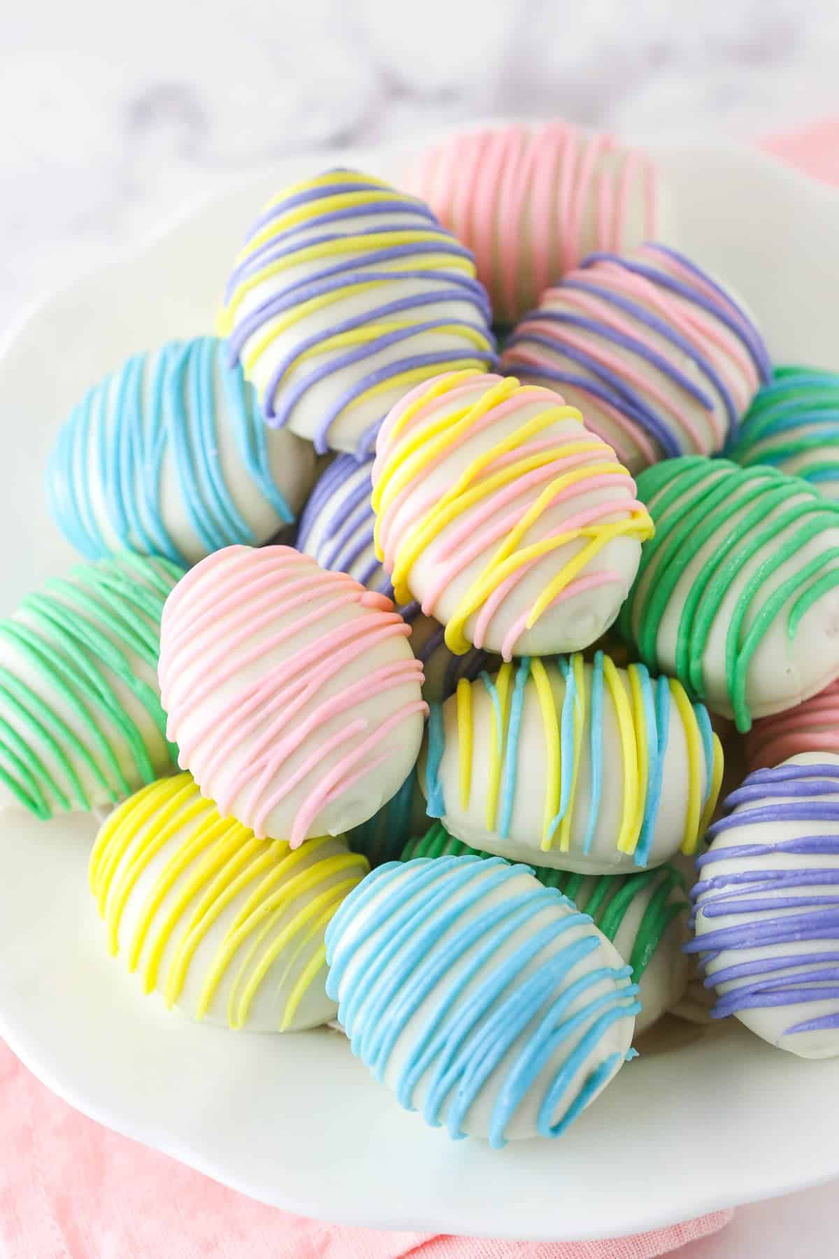 Easter egg Oreo cookie balls stacked on a white plate.