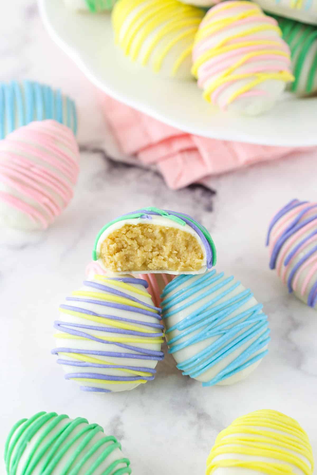 A couple of Easter egg Oreo cookie balls with the top cookie ball cut in half to show center.