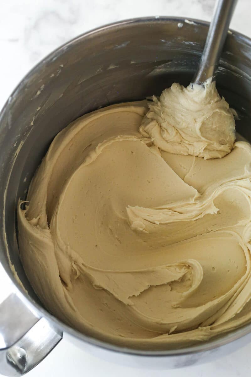 With layers of pumpkin cake, pecan praline crunch, and a caramel buttercream, this pecan praline pumpkin cake is impressive and delicious. Stirring buttercream frosting in a bowl