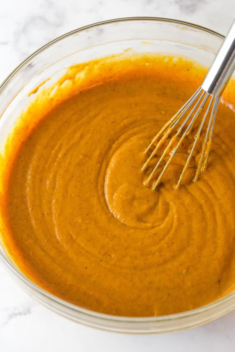 With layers of pumpkin cake, pecan praline crunch, and a caramel buttercream, this pecan praline pumpkin cake is impressive and delicious. Whisking pumpkin cake batter in a bowl