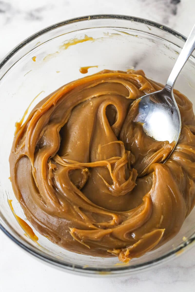 With layers of pumpkin cake, pecan praline crunch, and a caramel buttercream, this pecan praline pumpkin cake is impressive and delicious. A spoon in a bowl of caramel