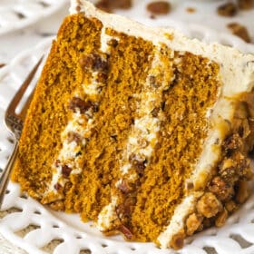 Close up of a slice of pecan praline pumpkin cake on a white palte