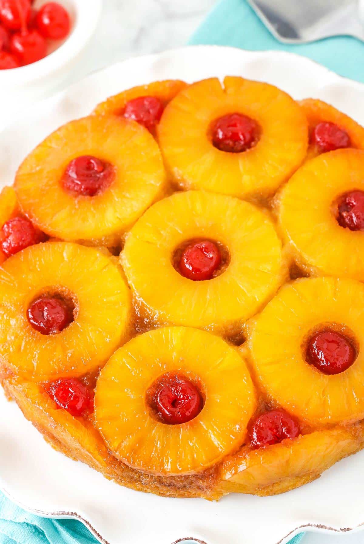 Soft and buttery with caramelized pineapple and cherries, this Pineapple Upside Down Cake has the perfect texture and lots of flavor! A pineapple upside down cake on a white platter.