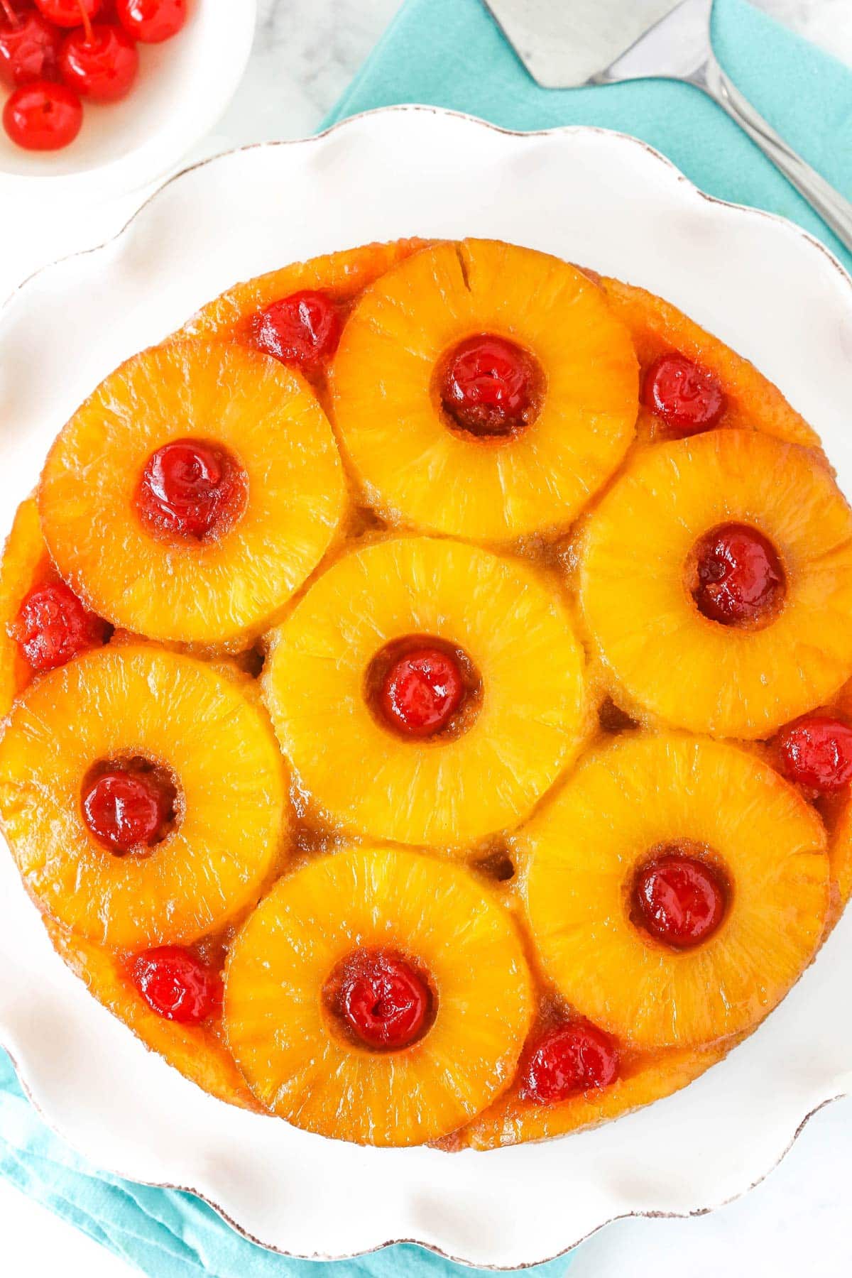 Soft and buttery with caramelized pineapple and cherries, this Pineapple Upside Down Cake has the perfect texture and lots of flavor! A pineapple upside down cake on a white platter.