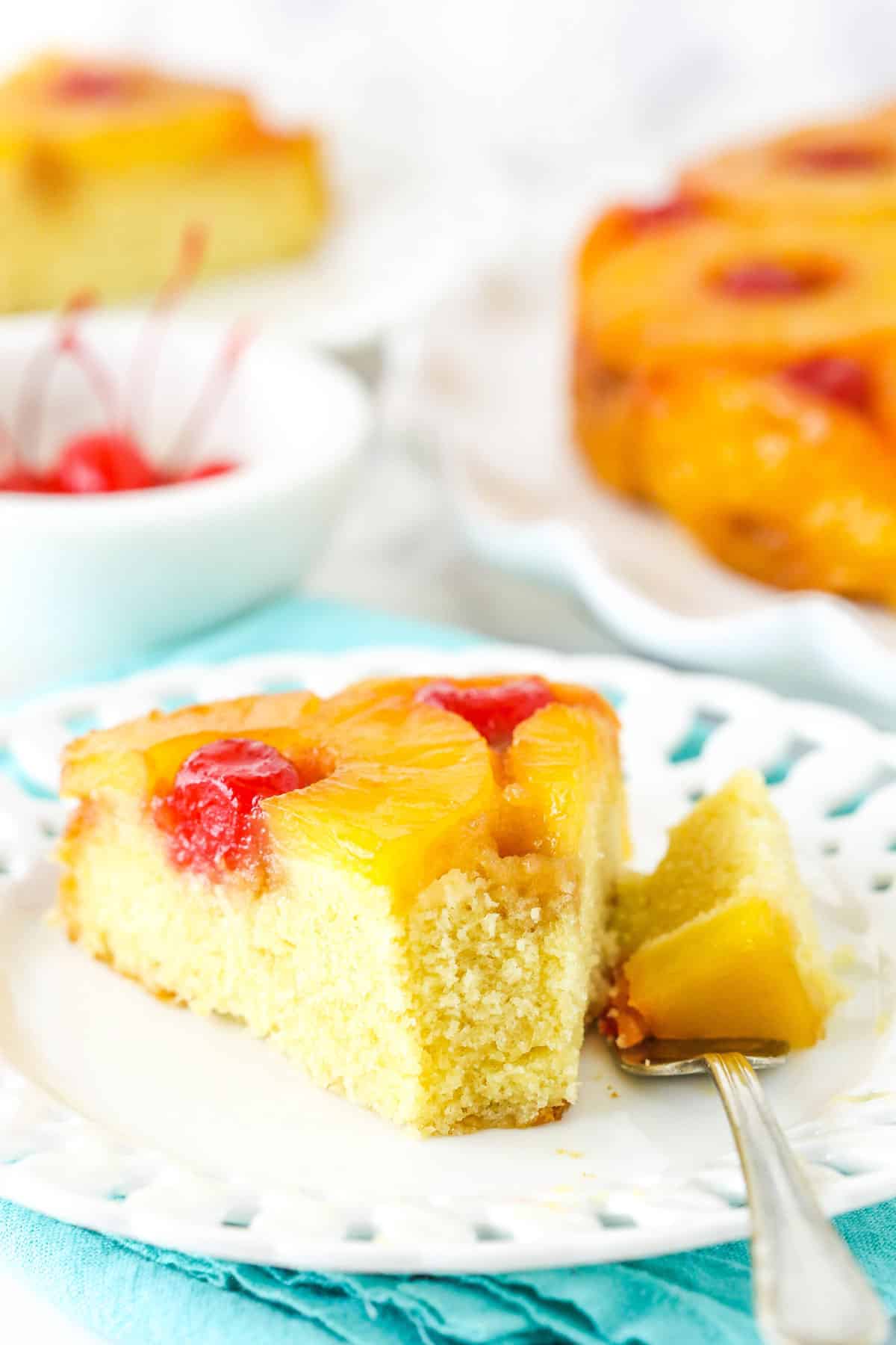 Soft and buttery with caramelized pineapple and cherries, this Pineapple Upside Down Cake has the perfect texture and lots of flavor! A slice of pineapple upside down cake with a bite removed on a fork.