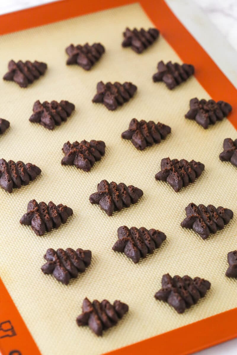 unbaked chocolate spritz cookies on baking mat