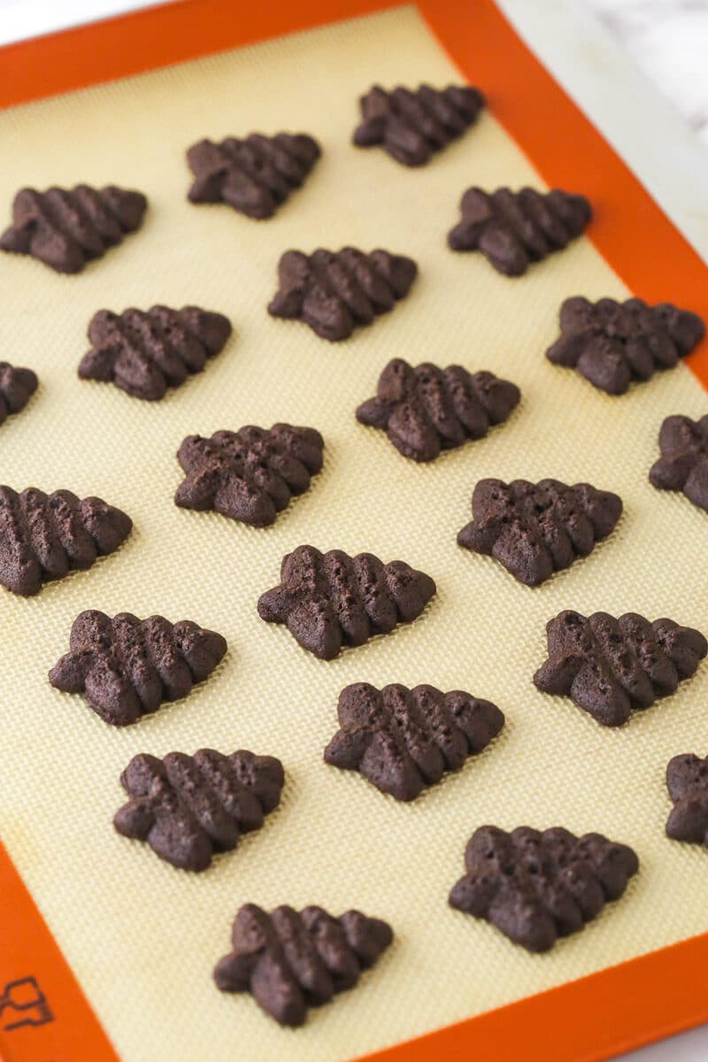 baked chocolate spritz cookies on baking mat