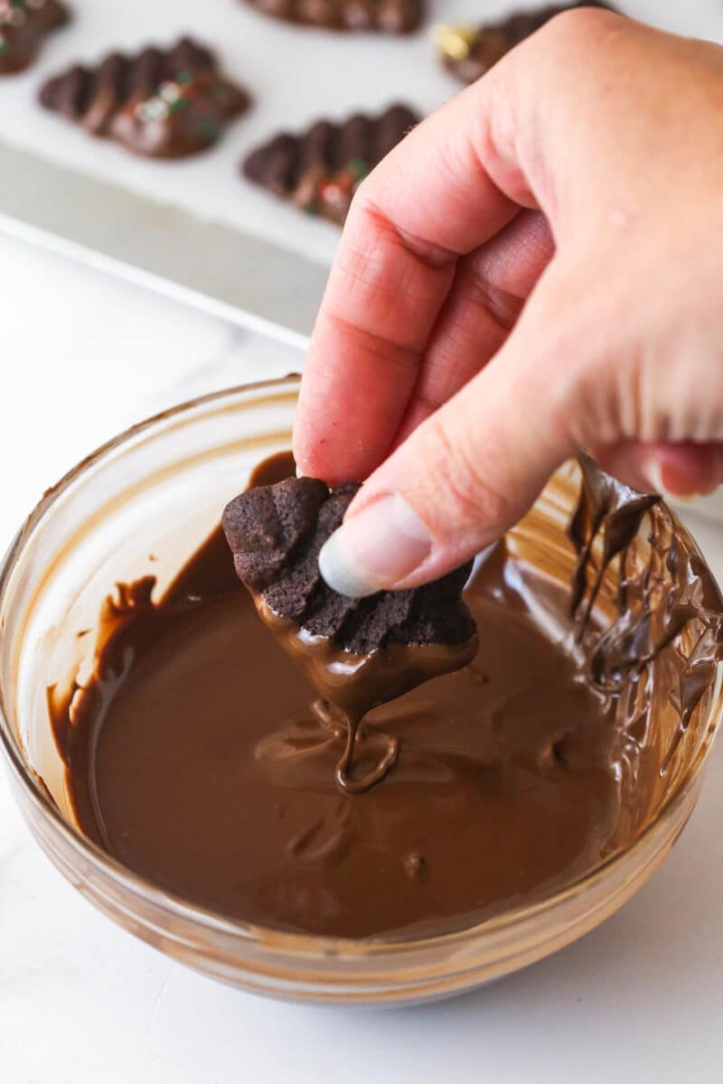 dipping chocolate spritz cookie into melted chocolate