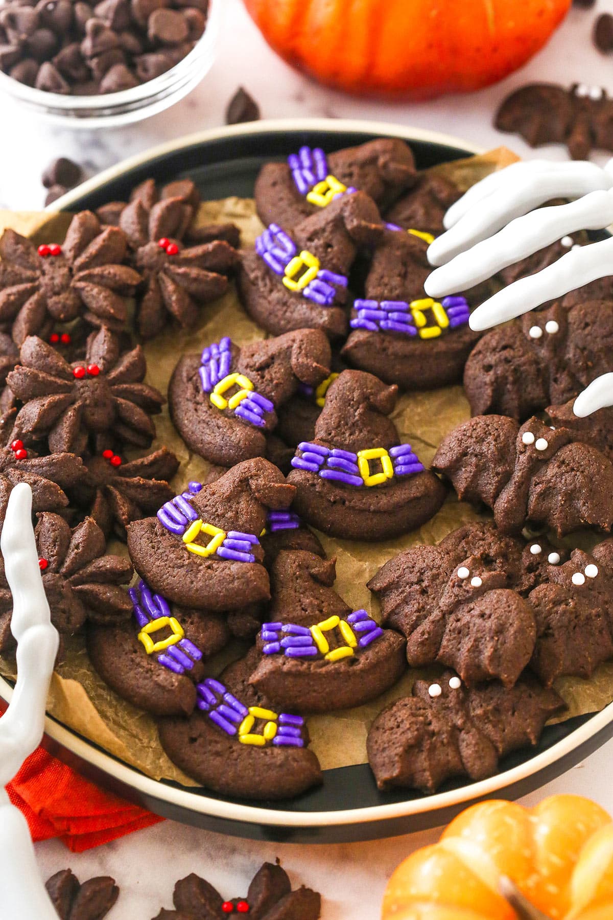 chocolate spritz bat, witch hat and spider cookies on dark colored plate