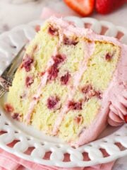 A slice of fresh strawberry cake on a white plate