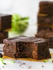 A fudgy zucchini brownie with a bite missing on a yellow napkin