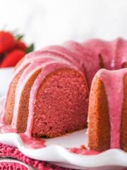 Strawberry pound cake on a serving platter with a slice taken out of it.