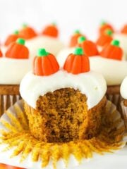 A pumpkin cupcake with a bite taken out of it.