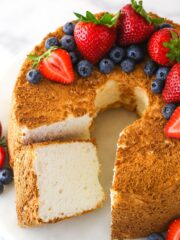 Overhead of angel food cake with a slice taken out of it topped with and surrounded by fresh berries.