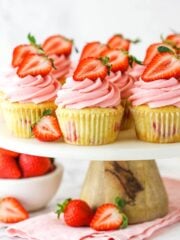 fresh strawberry cupcakes on marble and wood cake stand with strawberries around base