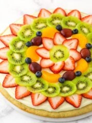 A fully decorated fruit pizza placed on a marble kitchen countertop